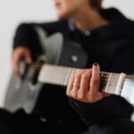 Focused close-up of a person playing an acoustic guitar, emphasizing fingers and strings.