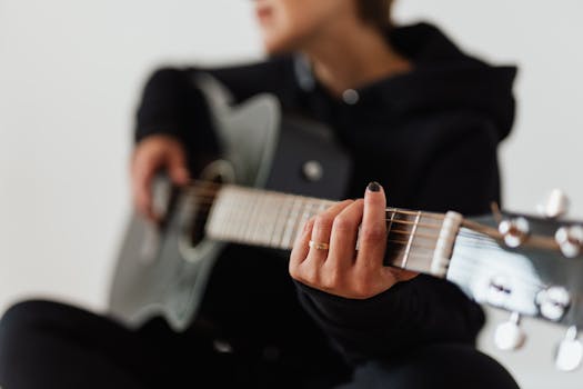 Focused close-up of a person playing an acoustic guitar, emphasizing fingers and strings.