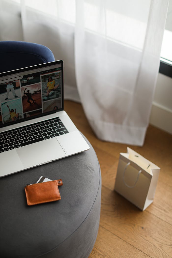 Photo of a laptop displaying images next to a wallet and shopping bag, indoors.